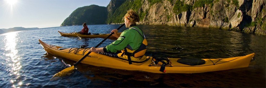 Des kayakistes pagayant prêts d’une falaise escarpée sur la rivière Saguenay.