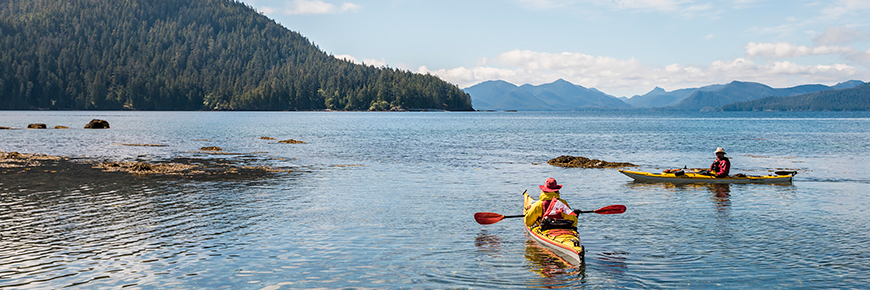  Kayakers paddle in Juan Perez Sound on a sunny day in July. Gwaii Haanas National Marine Conservation Area Reserve and Haida Heritage Site.