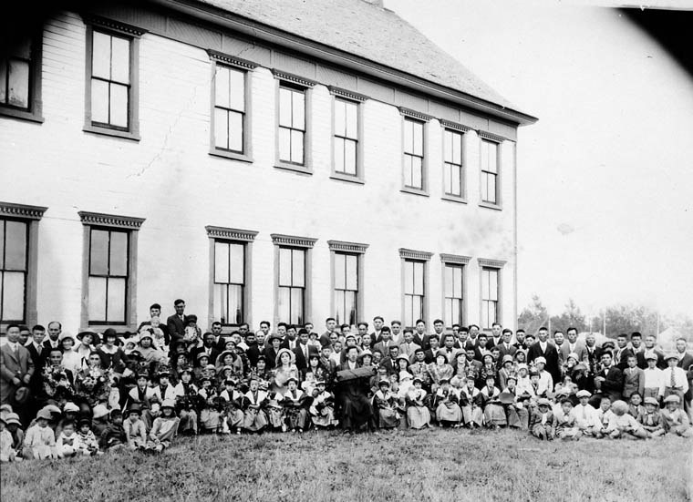 Group of kids and adults posing in front of a building