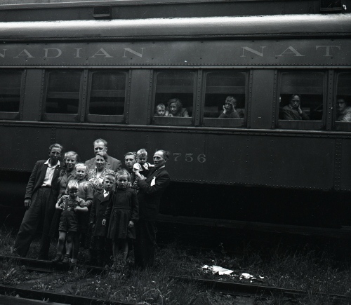 Historical photo of families in front of a train with people in it