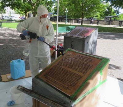 One person refurbishing a bronze commemorative plaque
