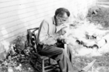 Black and white photo of a man seated and holding something in his hands