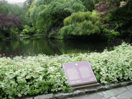 Plaque commémorative en bronze sur son socle dans un jardin