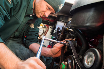Man in Parks Canada uniform uses a wrench to tighten an engine bolt.