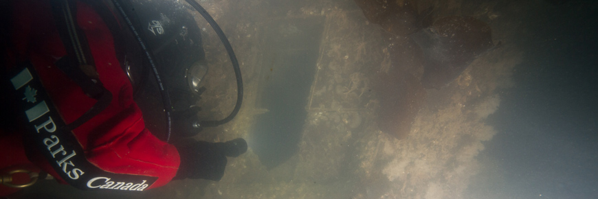 Underwater archaeologist points to oblong gap in shipwreck.