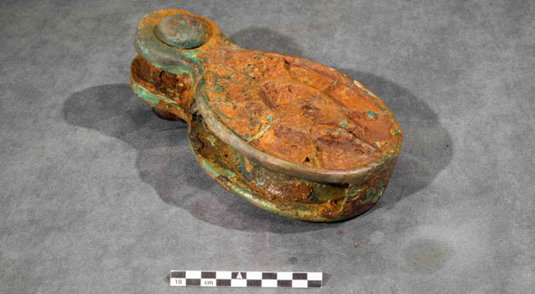 A rusty looking oval object with an integrated shackle.