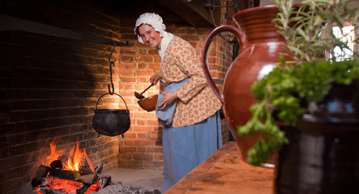 Une interprète costumée qui cuisine dans un four intégré à la cheminée