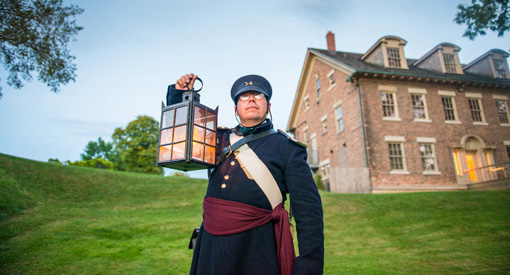 Officier tenant une lanterne face à la maison Hough au LHN du Fort- Malden