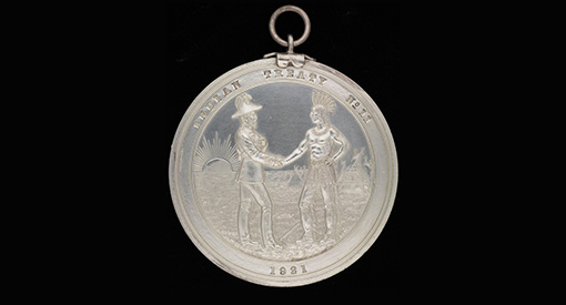Medallion representing an Indigenous and an Eurocanadian dressed in traditional outfits shaking hands
