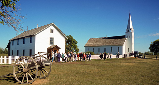 Des visiteurs à l'extérieur du presbytère au lieu historique national de Batoche