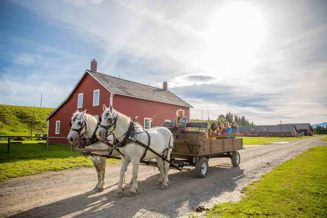 Un groupe de visiteurs apprécient une balade dans un chariot tiré par des chevaux au lieu historique national du Ranch Bar U.
