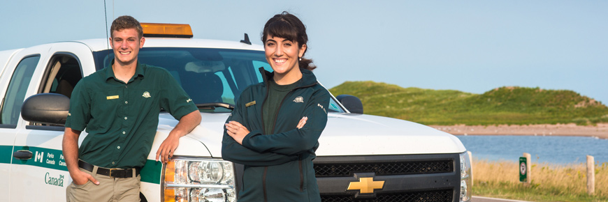 A man and woman standing in front of a Parks Canada truck