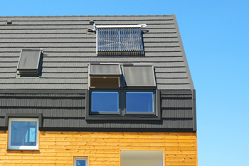 Toit d’une maison en bois passive dotée de puits de lumière et de panneaux solaires.