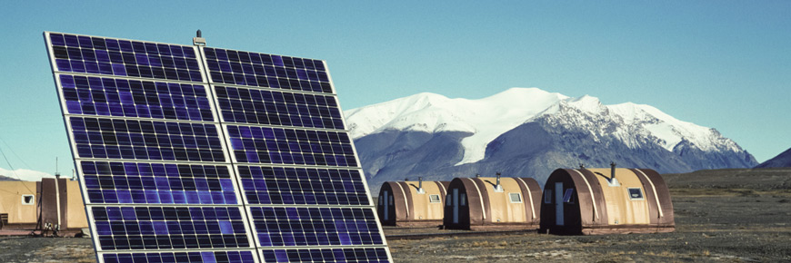 A solar array with huts in the background