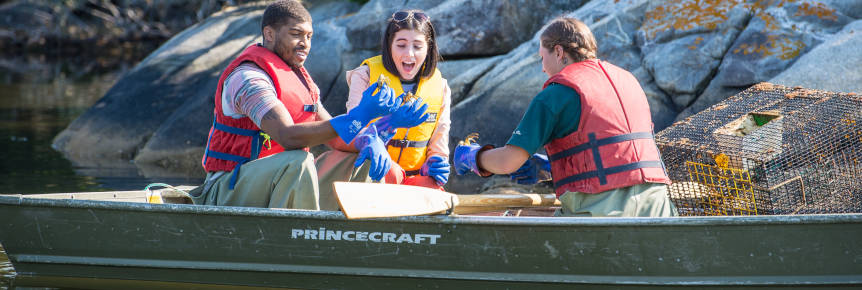 Trois personnes dans une barque avec un piège à crabe à côté d'eux.