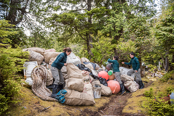 Trois personnes à Parcs Canada uniformisent les sacs d’ordures qui s’empilent