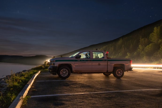 Un camion de Parcs Canada stationné près d’un plan d’eau pendant la nuit.