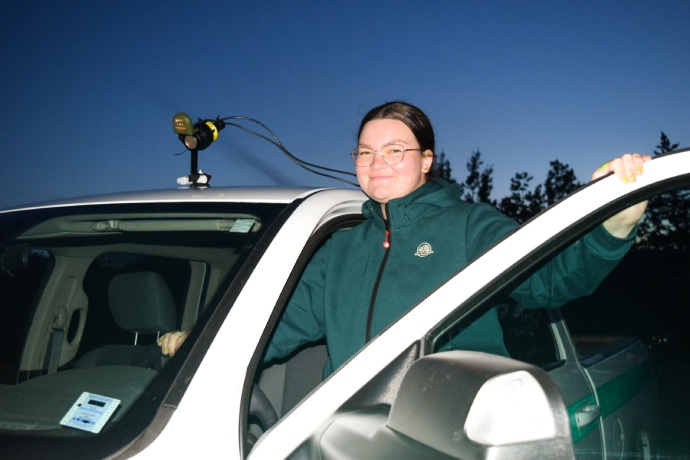 A Parks Canada staff person smiles as they enter the vehicle that is mounted with an acoustic monitoring device.