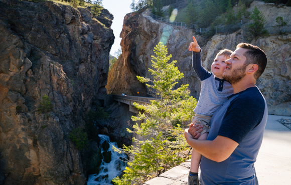 Un homme et son jeune enfant sont sur un sentier dans un canyon au parc national Kootenay.