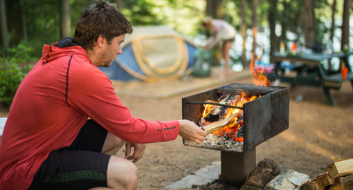 Un visiteur allume un feu dans un camping