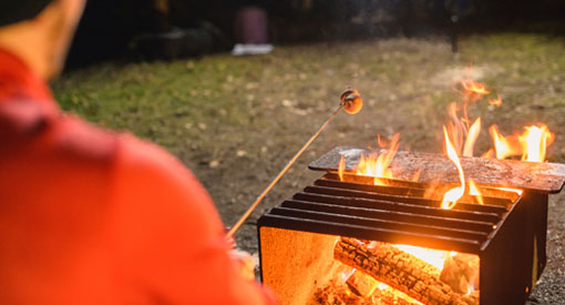 Visitor roasting a marshmallow over the firepit at Kouchibouguac National Park. 