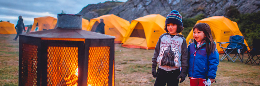 Two children gaze at a campfire at Signal Hill National Historic Site.