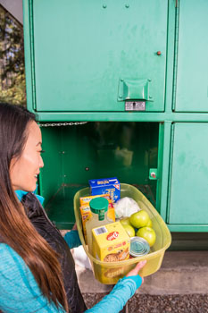 Une femme met des aliments dans un casier à nourriture.