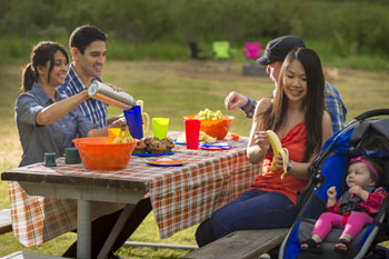 A family enjoys a meal at a picnic table.