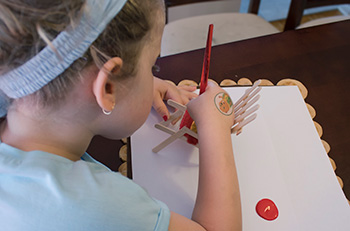 A young girl painting a mini red chair