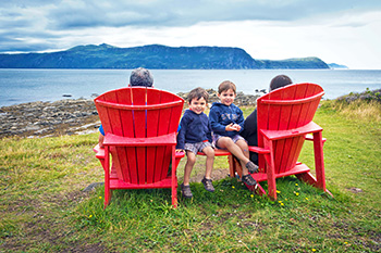A young family sitting on red chairs in Gros Morne NP