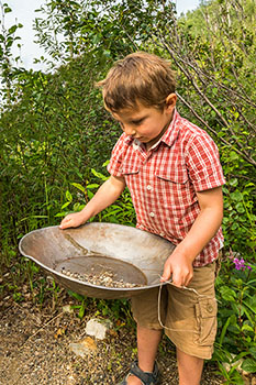 A child looks for gold in a pan