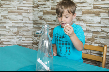 A boy is getting ready to place the egg on top of the bottle