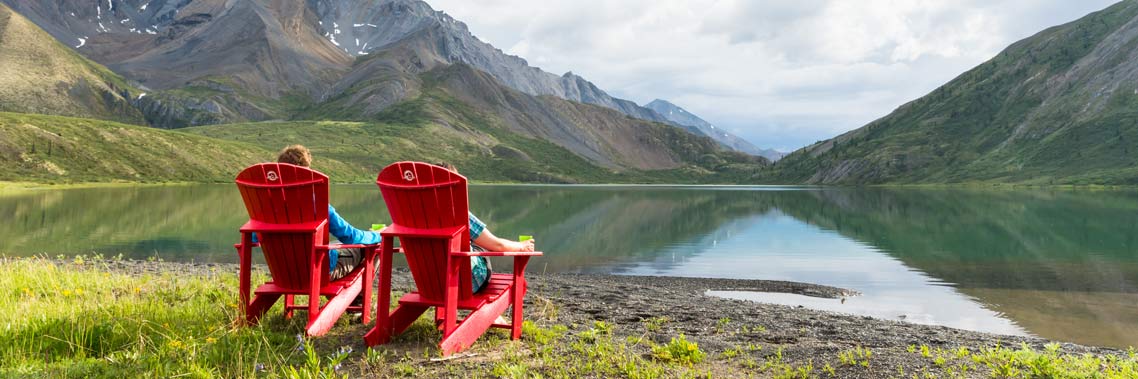 2 personnes assises dans les chaises rouges au lac Grizzly Bear. Réserve de parc national Nááts’ihch’oh.