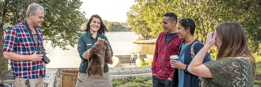 A Parks Canada guide shows visitors a beaver fur at the lookout point overlooking the junction of the Red and Assiniboine Rivers