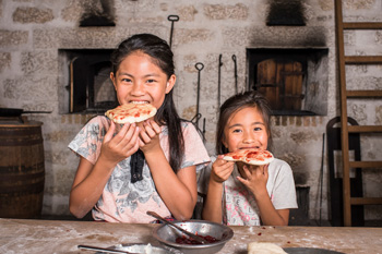Young visitors take a bite of freshly-baked bannock in the Bake House.