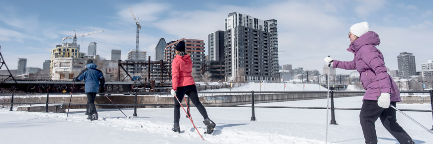 Trois adultes font du ski de fond en bordure du canal de Lachine à Montréal.