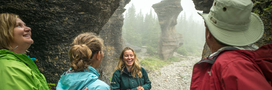 A Parks Canada Heritage Presenter leading an interpretation activity with the Lady of Niapiskau limestone monolith in the background.