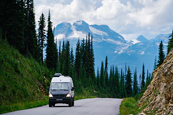 A van driving on the scenic Meadows in the Sky parkway with mountains in the background