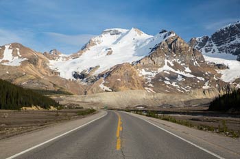 The scenic Icefields Parkway road surrounded by snow-capped mountains.