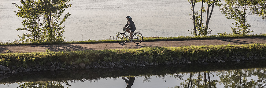 Une personne fait du vélo sur la piste qui borde le canal de Chambly
