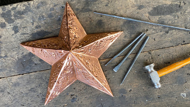 Une étoile en cuivre sur une table avec des clous et un marteau.