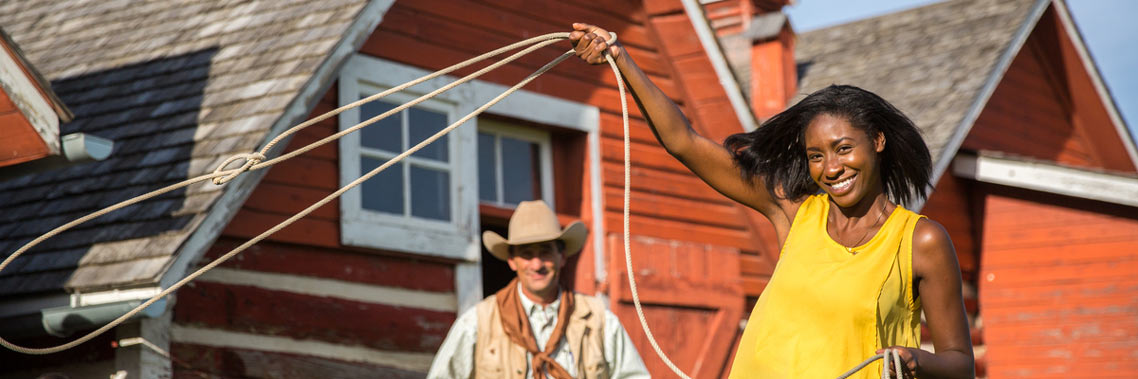 A young woman tries to throw a lasso in front a historic building.