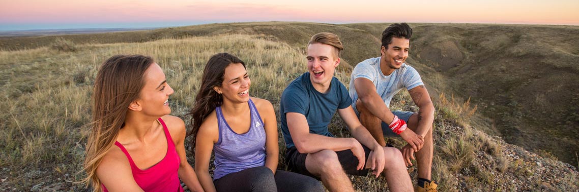 De jeunes adultes en randonnée prennent une pause sur le sentier de la Butte-70-Mile au parc national des Prairies.