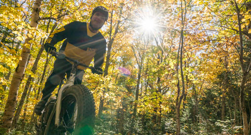 Un homme fait du vélo à pneus surdimensionnés dans la forêt.