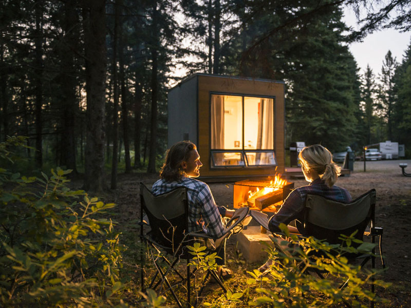 Visitors enjoy a campfire outside a MicrOcube at Wasagaming Campground.