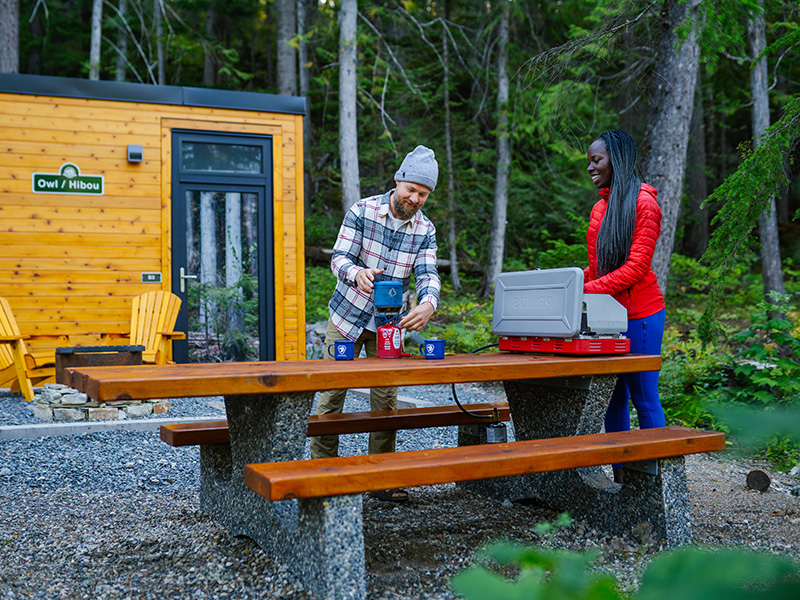 A couple prepares coffee on a picnic table at the MicrOcube in Mount Revelstoke National Park
