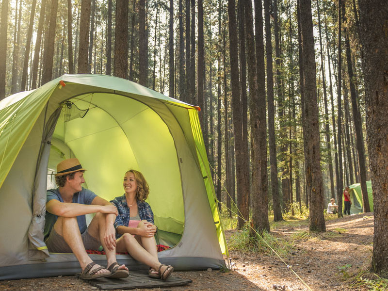 Un couple est assis dans une tente de l'un des emplacements de camping équipé.