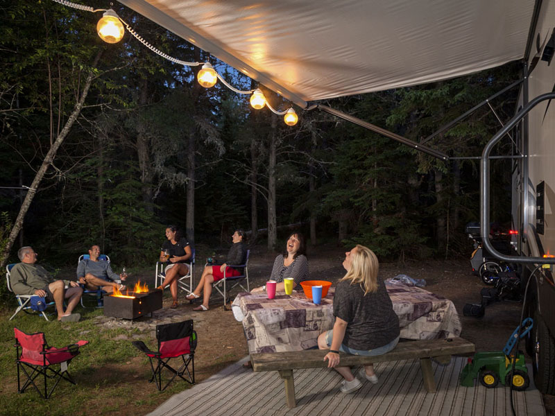 Adults enjoy a campfire in the evening near their caravan.
