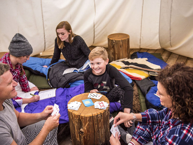 Une famille en pyjamas joue aux cartes à l'intérieur d'un tipi.