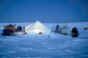 Tent and snowmobiles on the snow.